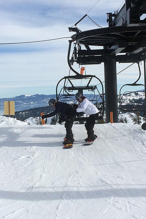 Senior Joel Castillo, dressed in black, and senior Juan Thunander, dressed in white, ride the ski lift to the top of the mountain. At the end of the lift, they attempted to get used to the snowboards but were caught off balance.