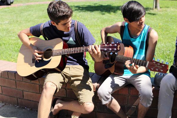 Students enjoy their lunchtime by strumming their guitars. 