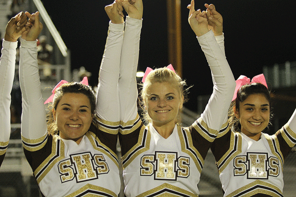 Cheerleaders root on Senior Anthony Nichols as he gets ready to kick the ball for an extra point.