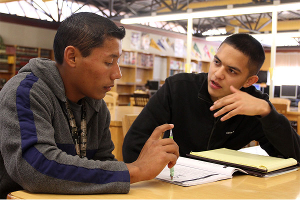 Senior Salvador Pasillas volunteers his afternoon to help one of the tutees with questions in a booklet compiled of practice CAHSEE questions. 
