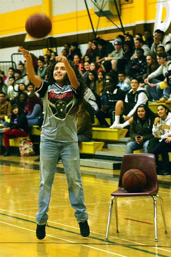 Junior Leslei Lopez, representing the girls basketball team, shoots three pointers during the Royal Assembly.