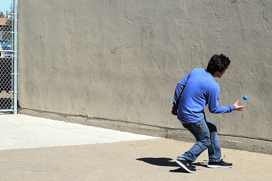 A student runs to catch the ball in a game of wall ball.