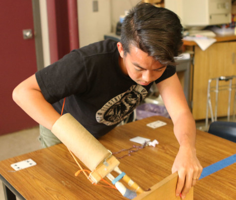 Andy Hoang demonstrates how he uses the  prostetic arm which Mesa student built.