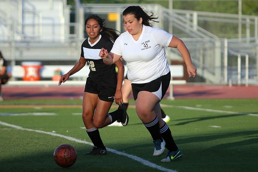 Junior Christina Rodriguez runs for the ball, as the defender tries to take it away.
