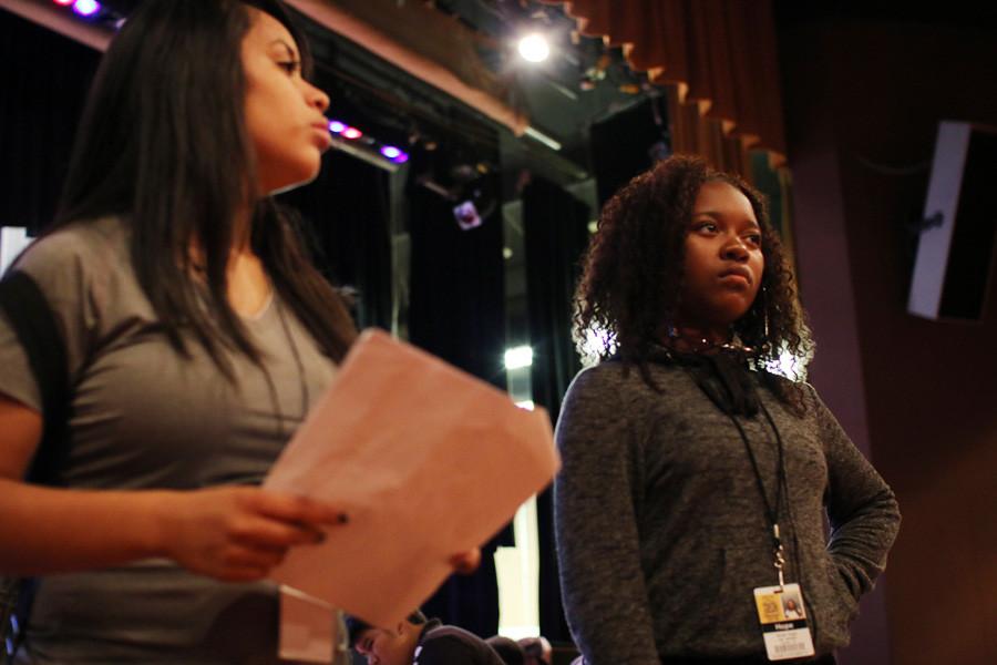 Two students prepare to recite their lines on stage.