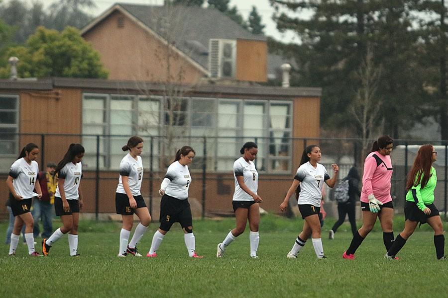 Varsity girls soccer put their heads down to shakes hands with their opponents. 