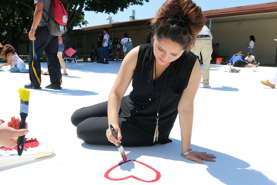 Leanna Arenas begins to paint on the quad starting with a heart. She added two smaller hearts and painted Senior Love. 