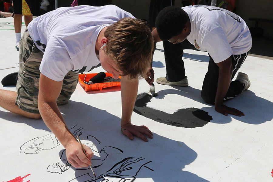 Seniors Cam Burnett and Jonathan Phillips sketches their drawing before painting. Burnett traced the letters YFG which stands for Young Fly God from clothing line Pink Dolphin. His design has been planned for 3 years and its inspired from his favorite mix tape. 