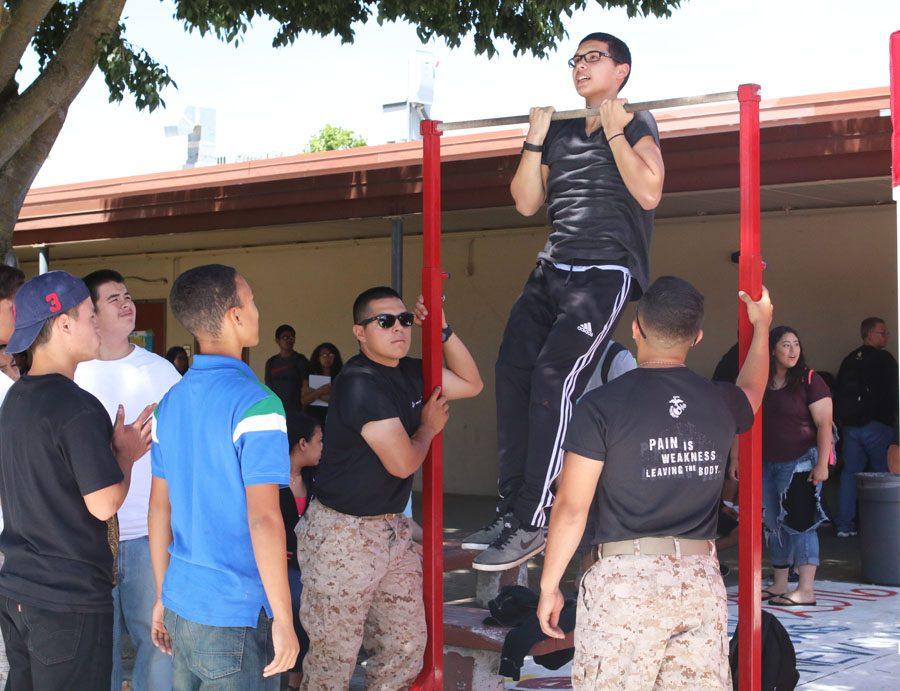 Students and marines watch as the student demonstrates his pull-up.
