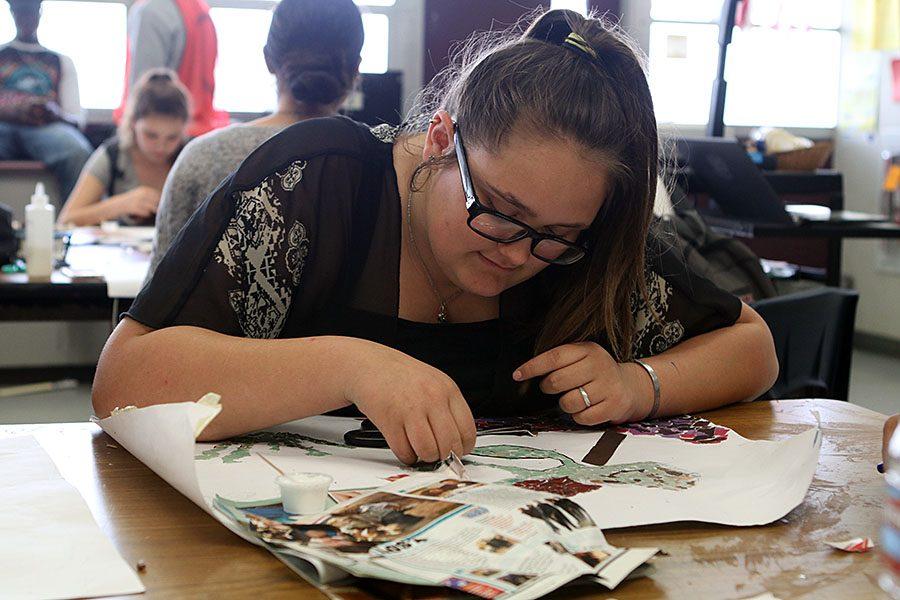 Shelby Craig, a freshman uses a toothpick to glue magazine pieces to her collage of Squirt from Finding Nemo.