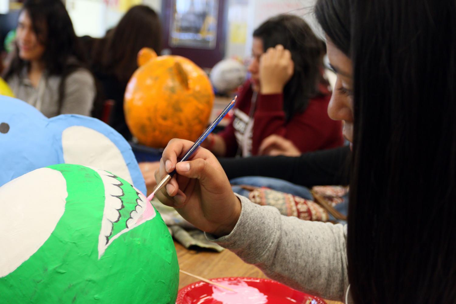 Freshmen Ivie Leyva is painting the mouth onto her paper mache character, Mike Wazowski.