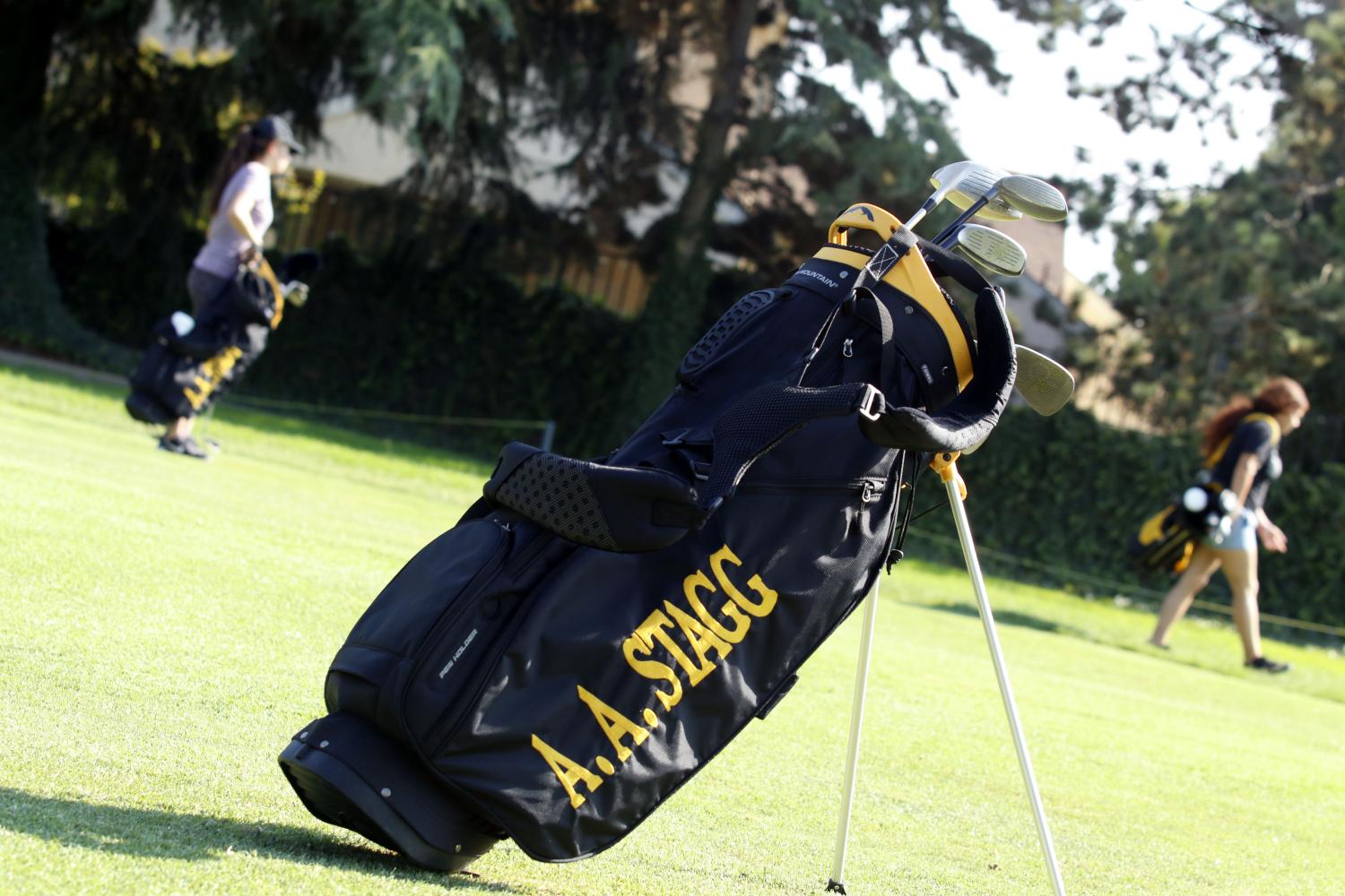 The girls carry their bags to go practice their swing. 
