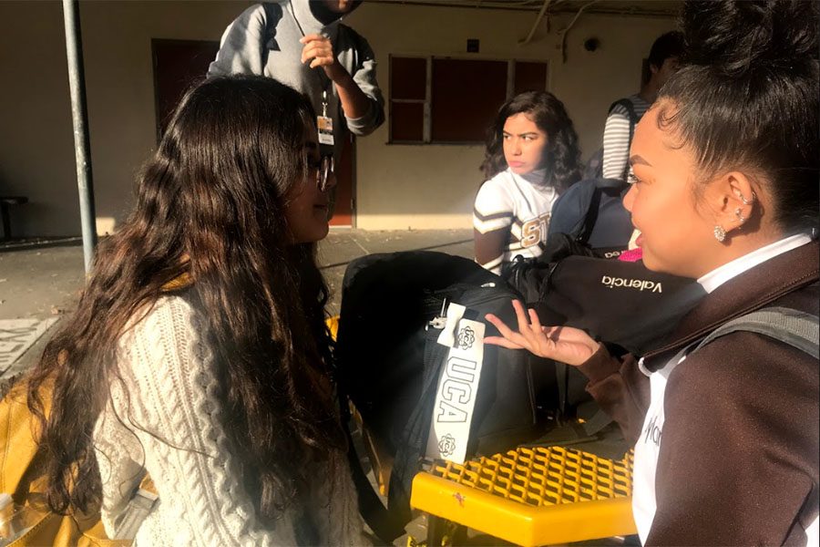 Sophomore cheerleaders Valencia Flores and Kaylan Daranikone discuss the cheer routine they will be performing at the first basketball tournament. 