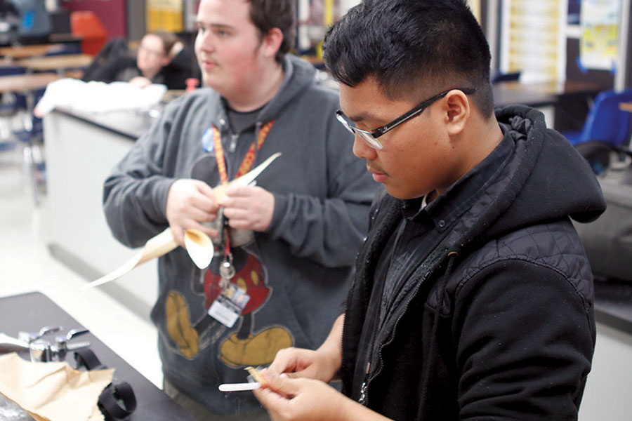 Senior Dylan Grace and junior Jake Moreno are constructing paper windmills. The class, AP Physics, was testing to see whose windmill would be able to pull up a weight the best.