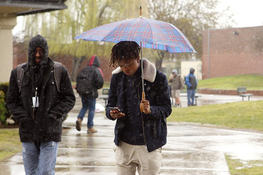 Junior Frederick Shaddai looks at phone while walking to his destination. 