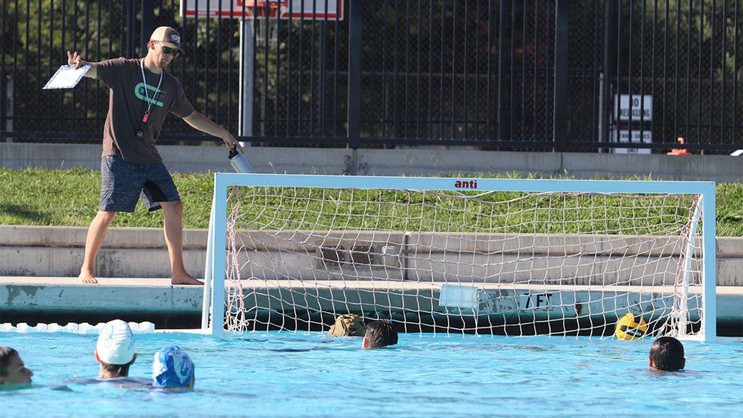 Coach Michael Bria demonstrates the concept of “setting a block” to his players to show them how to prevent their opponent from getting a shot off.