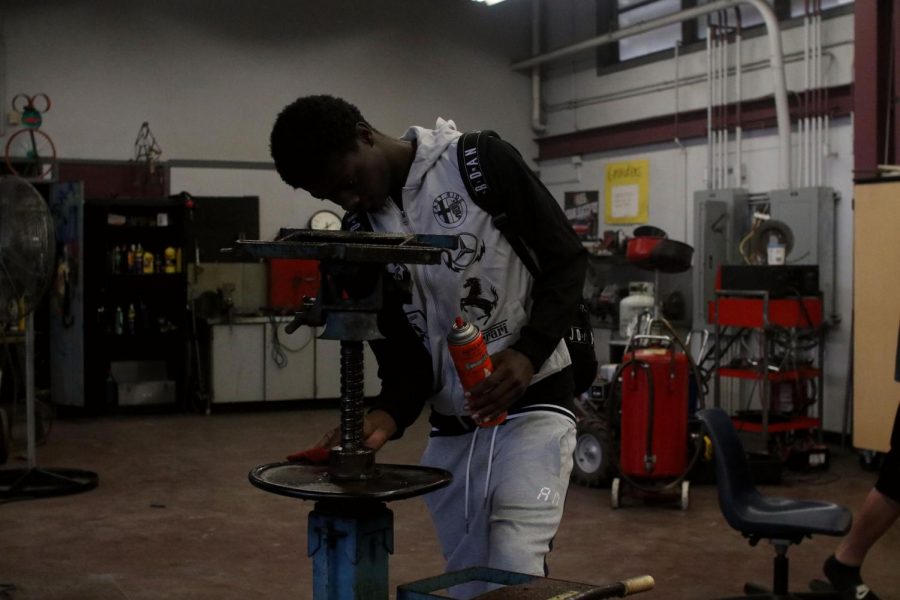 Lawson is oiling down a piece of equipment that will go beneath the car engine.