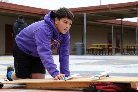 Freshman James Fenner kneels down in order to load his plane on the launcher to begin todays tests.