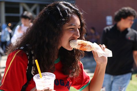 Junior Keimora Armstrong takes a bite of an elote with a Jamba Juice smoothie during the annual Club Rush event in September. 