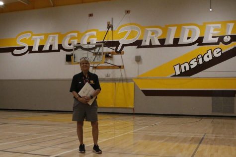 Coach Rosslyn Halekakis in the gym, posing in front of the school’s motto, which she made. (Xio Thor/StaggOnline)