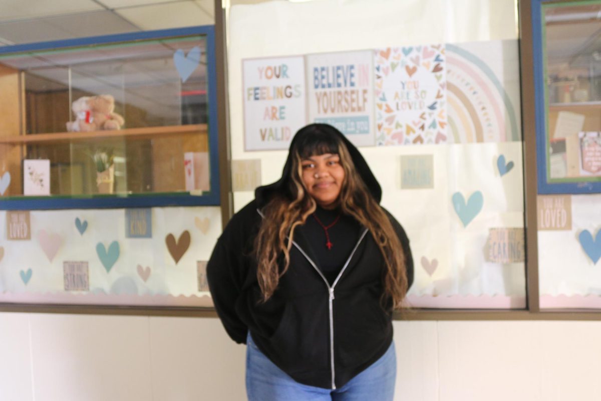 Yamilet Nolasco–Lopez smiles, taking a picture outside of her class, the background shows motivational posters. She proudly expresses herself and acknowledges how much she has improved. 
