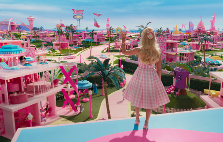 (Barbie, played by Margot Robbie, waves to her friends in Barbieland before getting in her car. She starts her day by saying hello to her friends. (Image from British Vogue)
