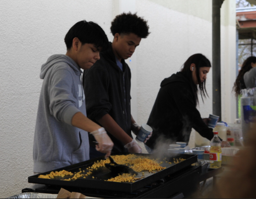 Rafael Esquivel and his fellow worker grill corn and sell elote at the Drama Stand during Spring Splash. The weather didnt interfere with their dedication to working and fulfilling their customers expectations. (Diana Mercado / StaggOnline)
