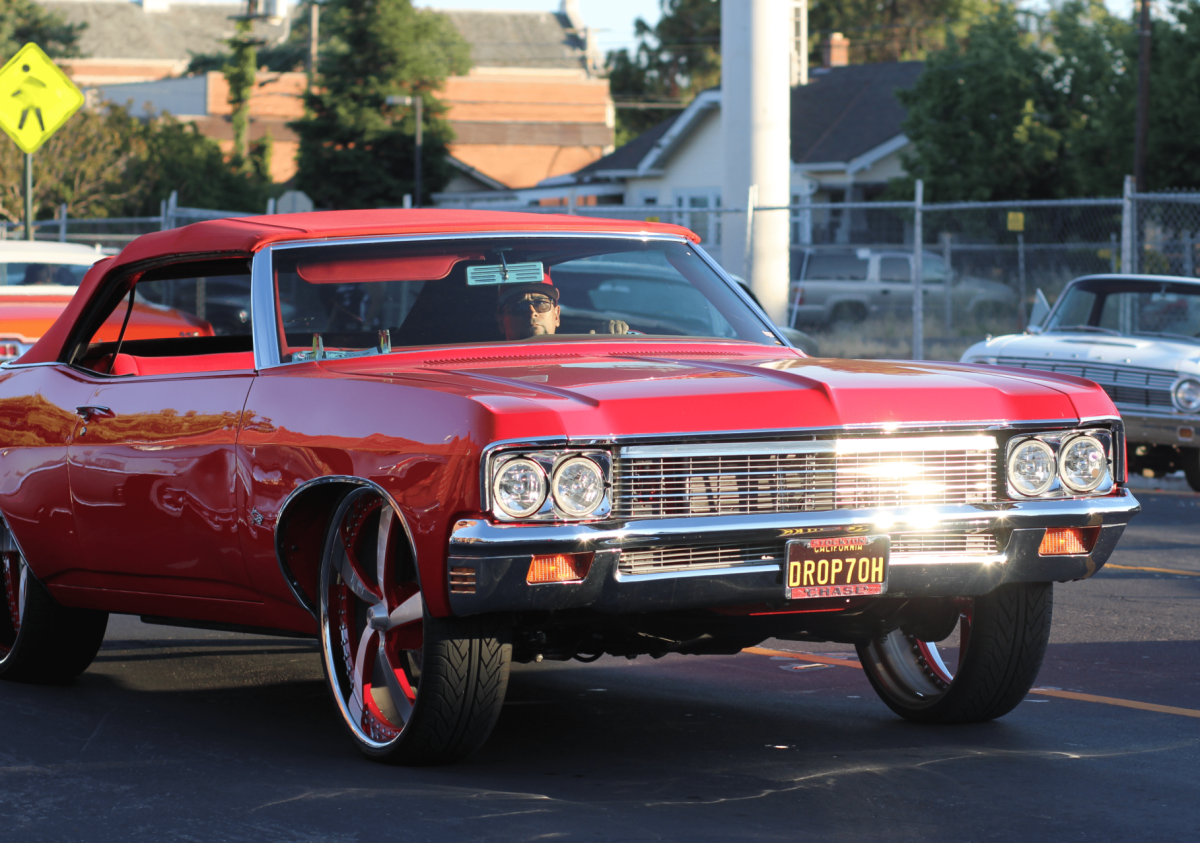 A red Donked or high-rise Chevrolet Impala cruising down Miracle Mile and Pacific, on its way to the event. Donking is a car modification that uses oversized wheels.