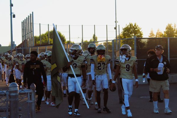 Delta Kings walking out to begin their season with a scrimmage against Edison Highschool and Sierra Highschool. The running back, Julian Benton, number 3, holding the “DK” flag. 