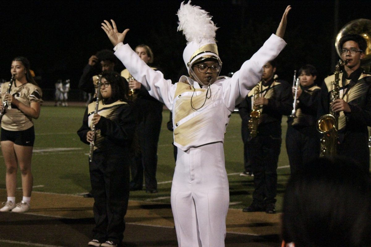 Drum Major Imani Stull leads the Stagg band in a white uniform at the end of their halftime performance. Stull also plays flag football for Stagg's team.