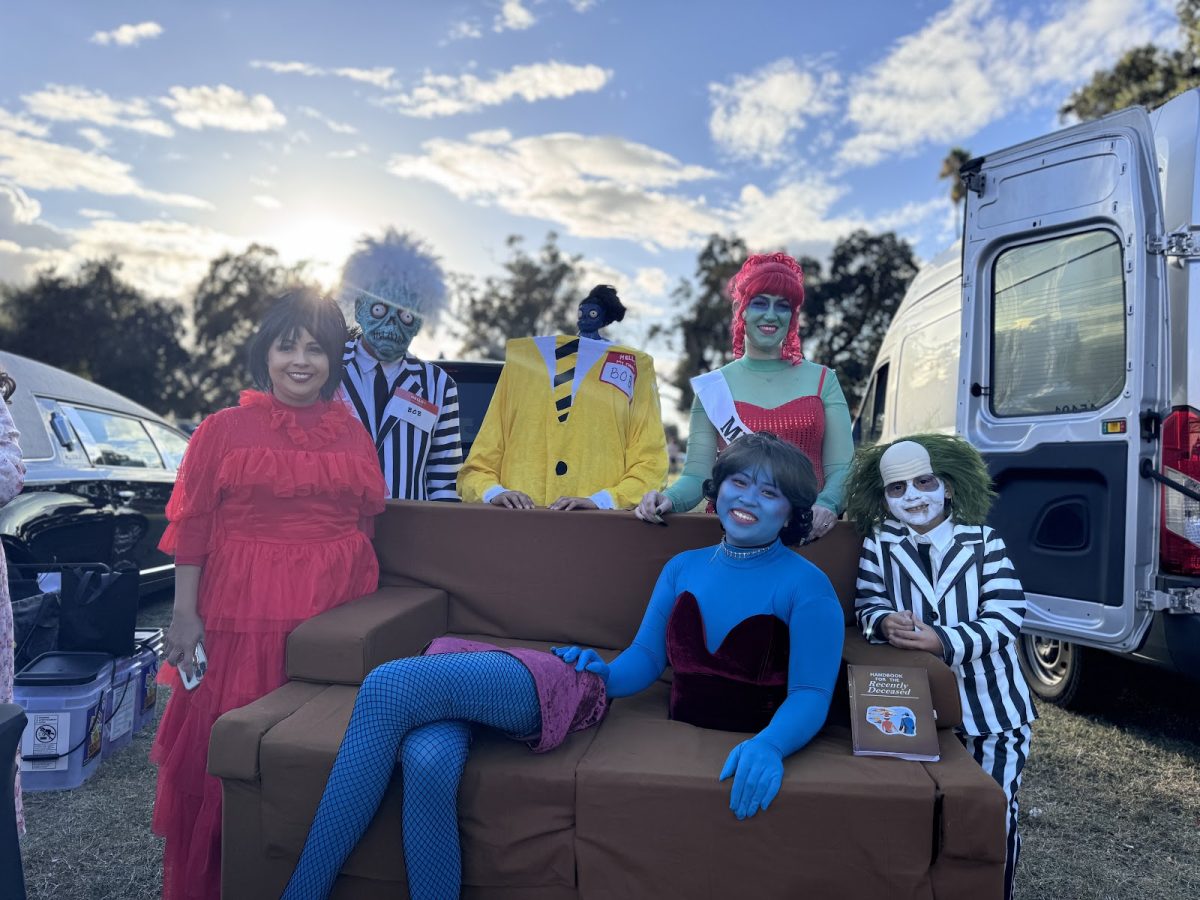 A ¨Beetlejuice¨ costume group pose for a photo. This group got a lot of attention for their unique costumes and had many people taking pictures.