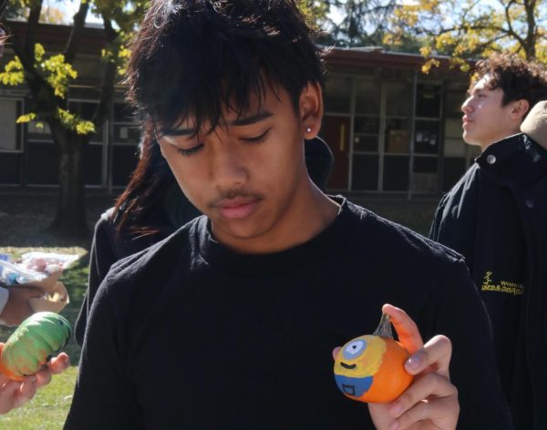 Sophmore Matthew Phang shows his pumpkin to the people in front of him. He painted a minion on the mini pumpkin he bought.