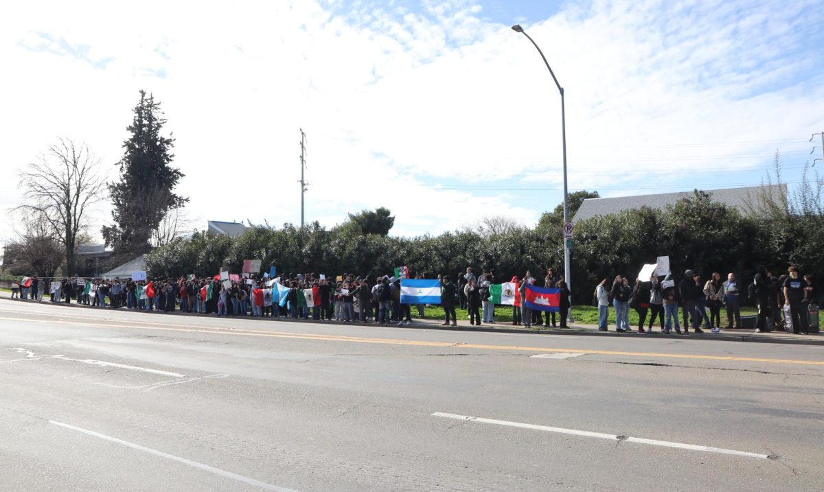 Protesters stand on Brookside Rd., waving their flags and posters to the traffic to spread awareness. Cars honk their horns as they drive by.