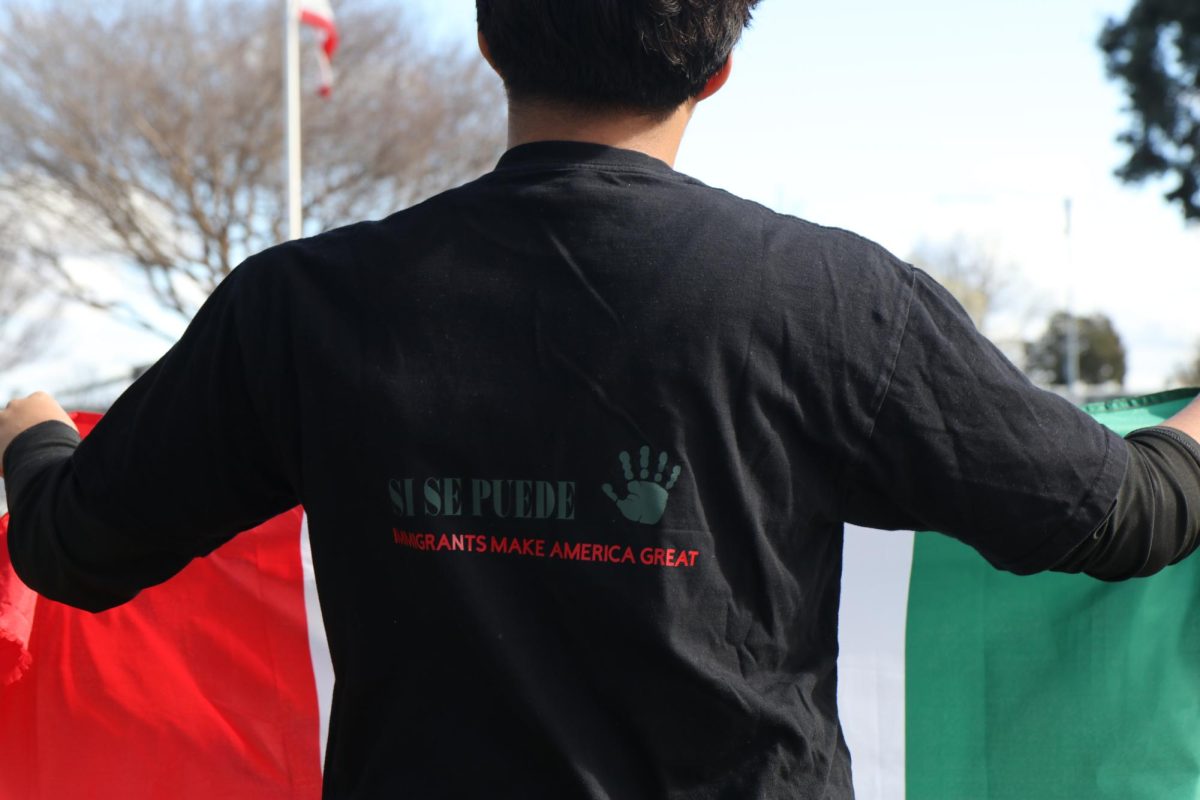 A student poses in a homemade shirt, showing support for the protest. They hold up the Mexican flag, the colors in his shirt reflecting the ones of the flag.