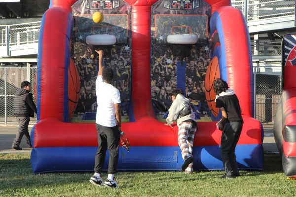  Seniors from the Class of 2025 play inflatable basketball during Senior Sunset. One student takes a shot while others wait their turn.