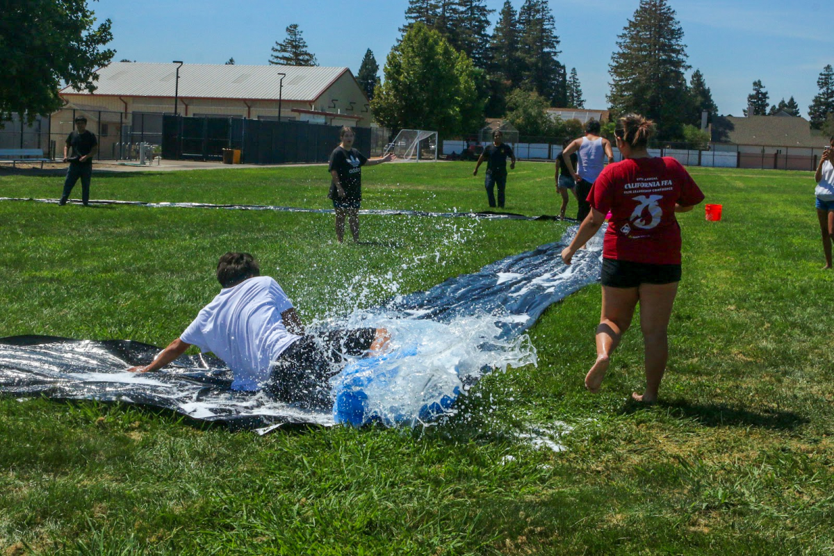 Participants are scattered around on a sunny day. As an FFA member was running he slid making a big splash and almost wetting another FFA member. 