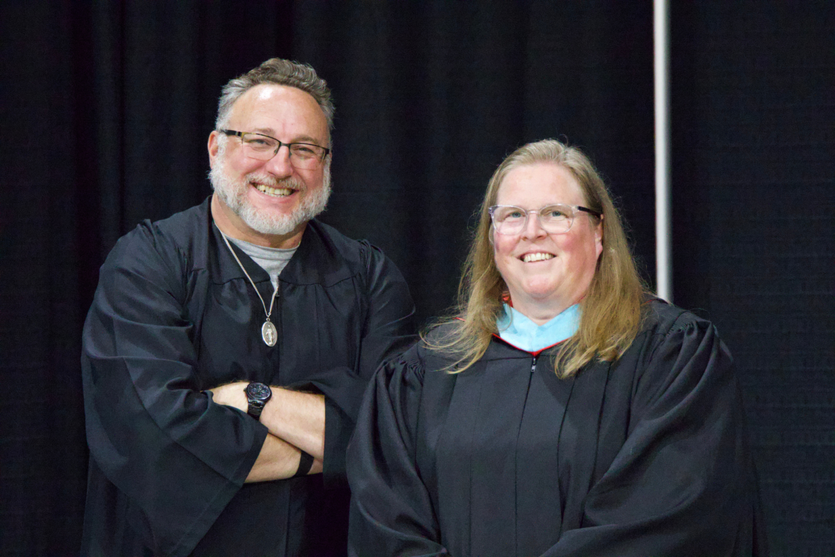 Mr. Barnes, left, and Ms. Markley, right, smile for a photo while listening to the valedictorian's speech.